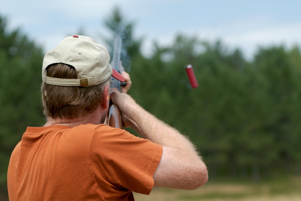 Coach supervising a young clay target athlete wearing eye and ear protection at a North Texas range